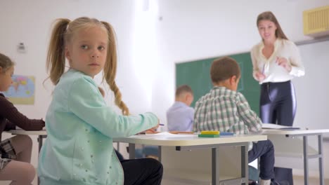 Porträt-von-Schulkind-am-Schalter-während-der-Unterricht-im-Klassenzimmer-in-der-Grundschule-auf-unscharfen-Hintergrund