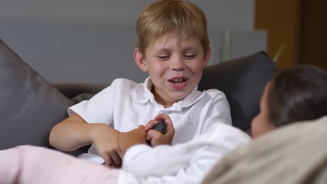 Little-Girl-and-Boy-Fighting-for-TV-Remote-Control-on-Sofa