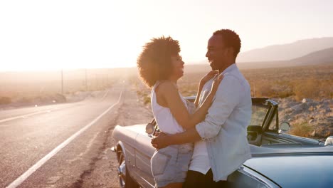 Young-couple-leaning-on-their-car-embracing-at-the-roadside