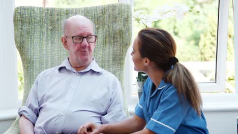 Ältere-Menschen-sitzen-im-Stuhl-und-im-Gespräch-mit-der-Krankenschwester-im-Altenheim