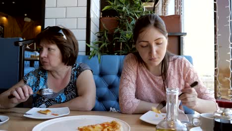 woman-and-a-girl-are-having-dinner-at-a-cafe,-eating-pizza