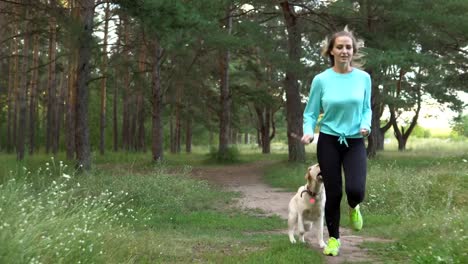 Junge-Frau-ist-mit-Hund-im-Wald-spazieren.