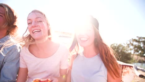 Teenaged-friends-sitting-together-outside-eating-pizza