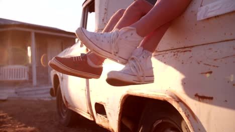 Teen-couple's-legs-hanging-out-of-vehicle-with-sun-flare