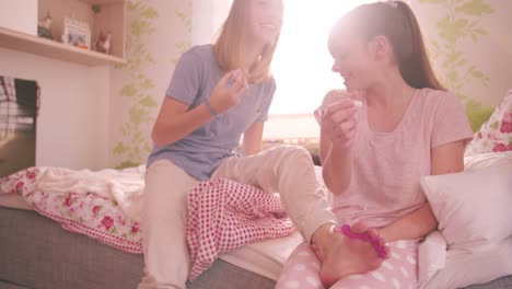 Teenager-Freunden-teilen-Nagellack-in-einem-farbenfrohen-Schlafzimmer