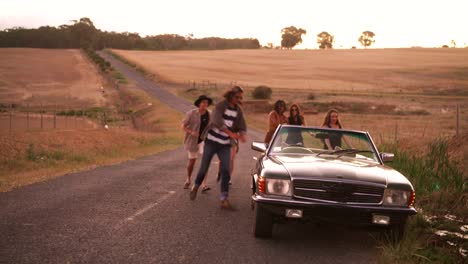 Adolescentes-amigos-corriendo-fuera-de-su-coche-al-anochecer