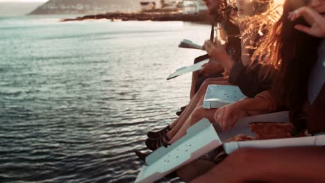 Hipster-style-teenager-friends-eating-pizza-on-the-dock