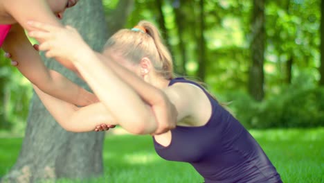 Blonde-woman-stretching-with-help-of-friend-outdoor.-Sport-woman-stretching