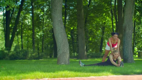 Fitness-woman-doing-stretching-exercise-on-green-grass-at-park