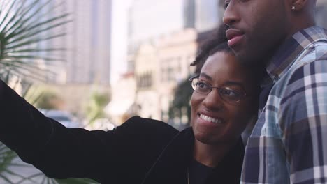 Pareja-afroamericana-en-una-ciudad-tomando-fotos-junto-con-un-teléfono-celular,-de-cerca