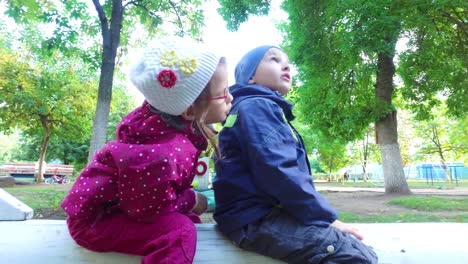 Blond-boy-and-girl-with-glasses-simulate-flying-a-plane.-Children-play-on-the-playground-and-laugh.