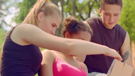 Junge-Leute-zu-beobachten-Foto-auf-Tablet-im-Freien.-Junge-Freunde,-die-Spaß