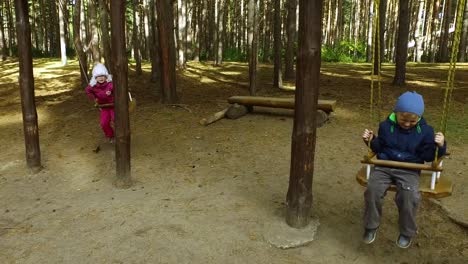 Muchacho-rubio-y-niña-niño-niño-con-gafas-que-se-divierten-en-el-patio-de-recreo-en-el-parque.-Los-niños-pequeños-tienen-diversión-fin-de-semana-junto.