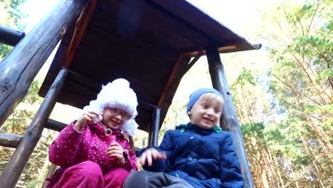 Blond-boy-and-girl-with-glasses-blow-bubbles-in-the-playground.-Children-are-very-fun.-They-have-fun-and-laugh.