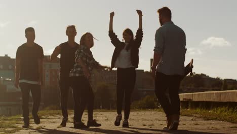 Grupo-de-adolescentes-felices-riéndose,-levantando-las-manos,-saltar-mientras-se-mueve-hacia-adelante-a-la-cámara.