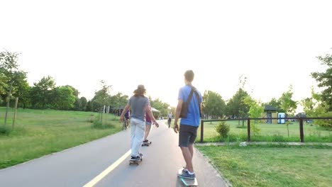 Frau-und-zwei-Männer-Skateboarden-auf-Rad-Weg-bei-Sonnenuntergang