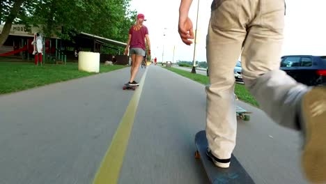 Niedrigen-Winkel-Blick-auf-zwei-Männer-und-eine-Frau,-die-bei-Sonnenuntergang-skateboarding