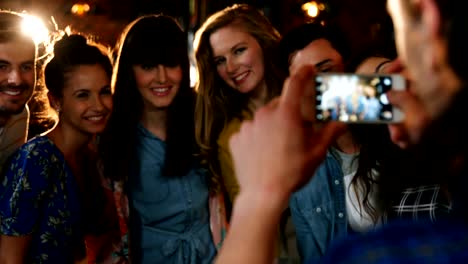 Woman-clicking-photo-of-friends-on-mobile-phone