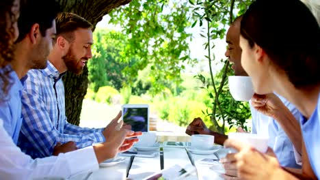 Gruppe-von-Freunden-diskutieren-über-digital-Tablette-auf-Terrasse