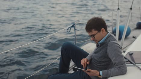 Man-uses-tablet-on-a-yacht-in-the-sea.