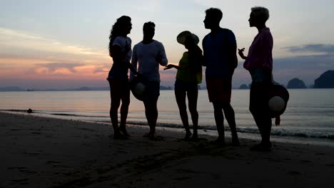 Gente-hablando-en-la-playa-al-atardecer,-la-comunicación-del-grupo-de-jóvenes-turistas