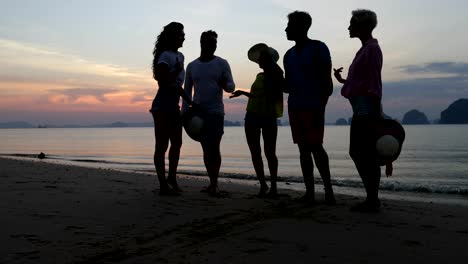 Menschen,-die-am-Strand-im-Sonnenuntergang-reden,-Gruppenkommunikation-junger-Touristen