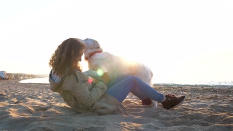 Hembra-joven-rápida-jugando-con-perro-retriever-en-la-playa-al-atardecer