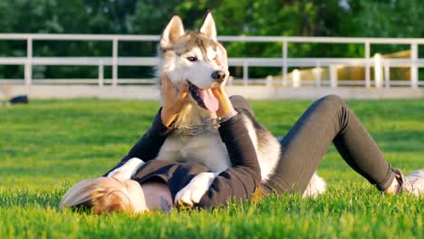 Schöne-junge-Frau,-die-das-Spiel-mit-lustigen-husky-Hund-draußen-im-park