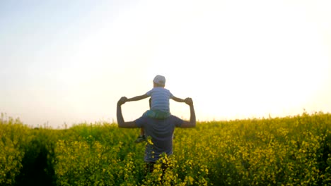 Family-walk,-men-with-boy-on-neck-moving-through-field,-daddy-and-children-go-by-field-with-raised-arms