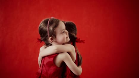 Two-little-girls-hugging-on-a-red-background