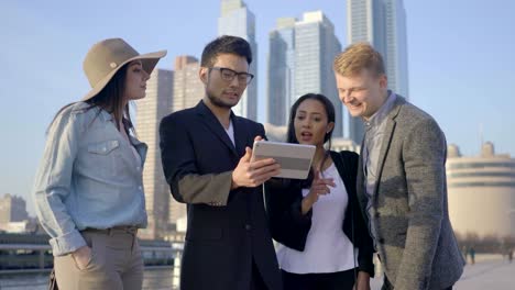 Young-Gender-Mixed-Diverse-Group-of-Friends-Using-Digital-Tablet.-Talking,-Discussing-und-Cheering-in-the-City.