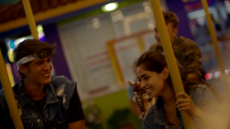 Young-hipster-friends-having-fun-on-funfair-carousel-ride