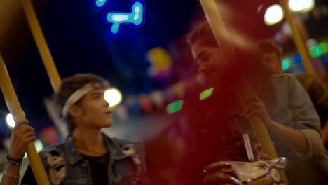 Teenage-couple-kissing-on-amusement-park-carousel-ride