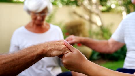 Senior-friends-holding-hands-and-meditating-in-garden-4k