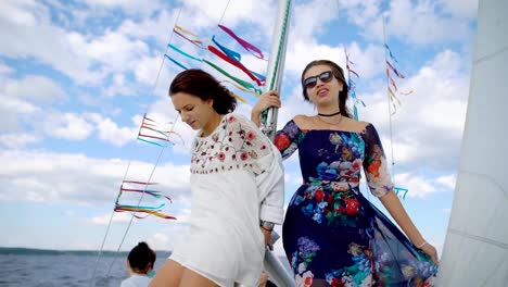 Stylish-girls-posing-happily-on-sailboat-while-having-party