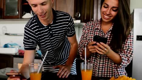 Couple-Use-Cell-Smart-Phones-Talking,-Young-Woman-And-Man-In-Kitchen-Studio-Embracing-Chatting-Online-Modern-House-Interior