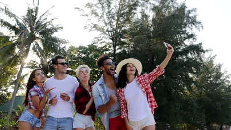 Menschengruppe-Aufnahme-Selfie-auf-Zelle-Smart-Handys-sprechen-glückliche-Männer-und-Frauen-über-tropische-Palmen