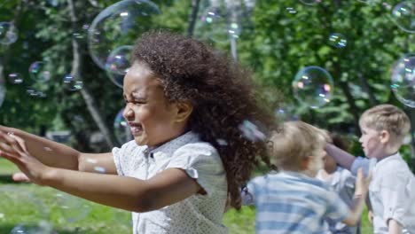 Glücklich-afrikanisches-Mädchen-fangen-Seifenblasen-auf-Kids-Party-im-Park