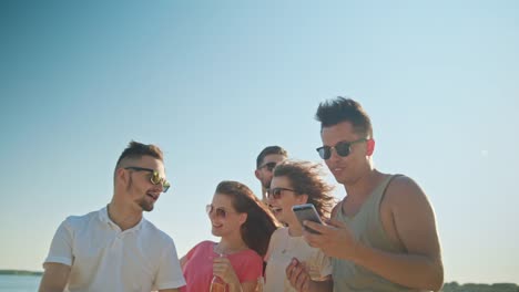 Jóvenes-divirtiéndose-en-la-playa-utilizando-teléfonos