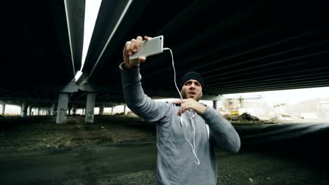 Athlete-man-having-video-chat-on-smartphone-with-his-trainer-after-workout-at-urban-location-outdoors-in-winter