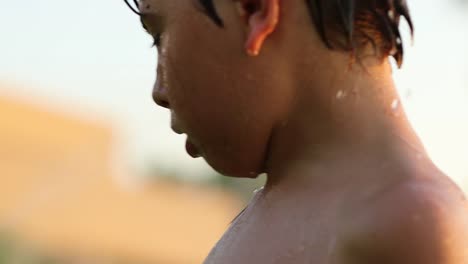 Child-gesturing-with-hands-and-face-not-wanting-water-sprinkle-to-hit-his-face.-Young-boy-4k-clip-resolution-playing-with-water-sprinkles-outside-in-the-lawn