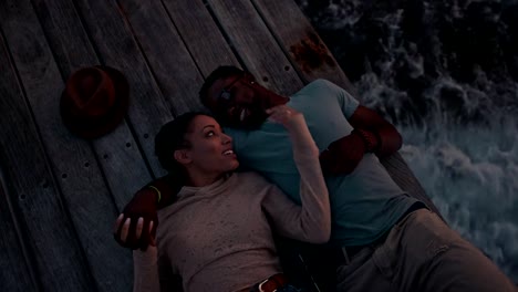 Young-romantic-multi-ethnic-hipster-couple-flirting-lying-down-on-jetty