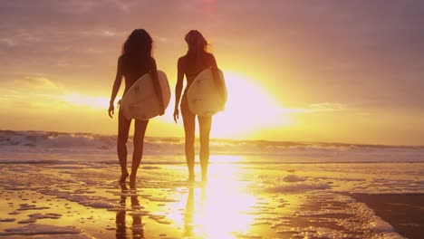 Schöne-schlanke-Surfer-Girls-Strand-Sonnenuntergang-Blick-auf-Wellen