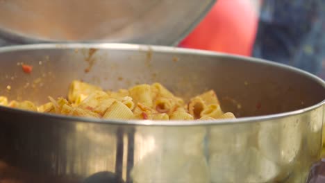 Young-happy-kids-preparing-eating-lunch-pasta-in-summer-camp-outside-on-sunny-day-in-park-serving-food-from-pot-pan-slow-motion