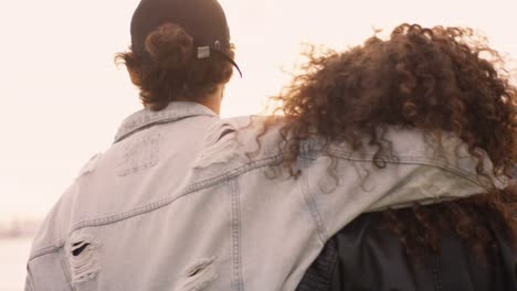 Young-couple-is-walking-at-the-harbor-while-sun-is-going-down