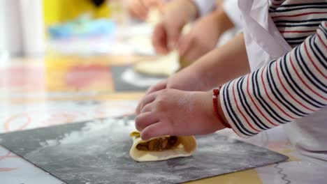 Baby-Hand-kleine-Köche-Torte-aus-Mehl-und-Teig-unter-Anleitung-eines-erfahrenen-Lehrers-kocht,-Nahaufnahme,-master-Klasse-Unterricht-Gruppe-Kinder-kochen-Kuchen-mit-den-Eltern