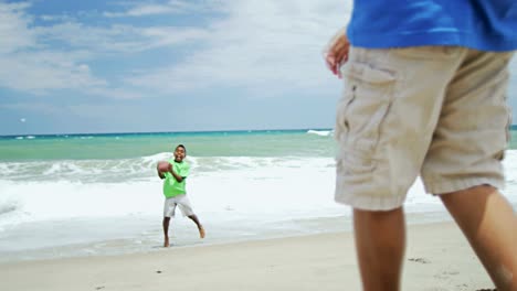 Afrikanische-amerikanische-jungen-Ballspiele-am-Strandurlaub