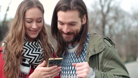 Young-happy-couple-using-smartphone-in-a-city.