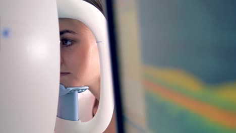 Close-up-of-young-woman's-head-being-put-on-an-optical-machine-while-her-eyes-are-examined