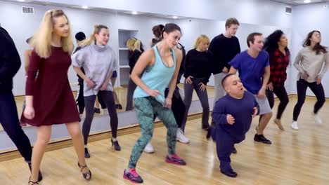 Young-group-of-people-and-little-man-dances-together-in-light-studio